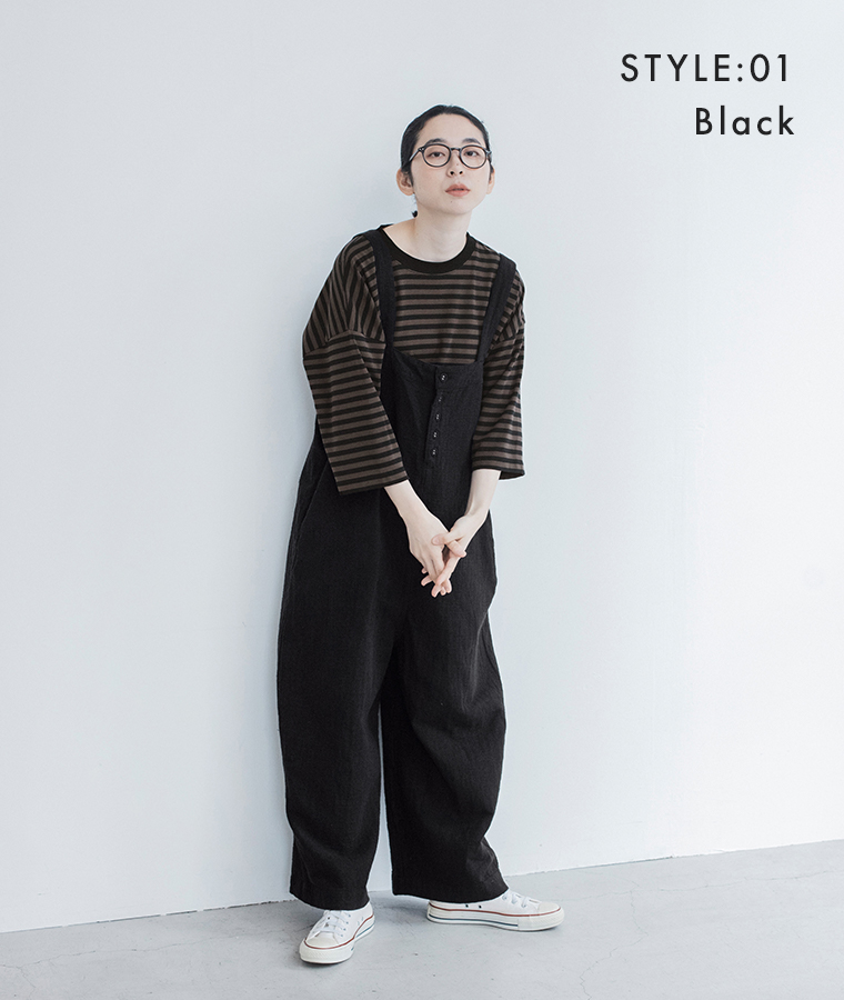 ブラックのサロペットにブラウンのボーダーTシャツと白いスニーカーを合わせた全身スタイル