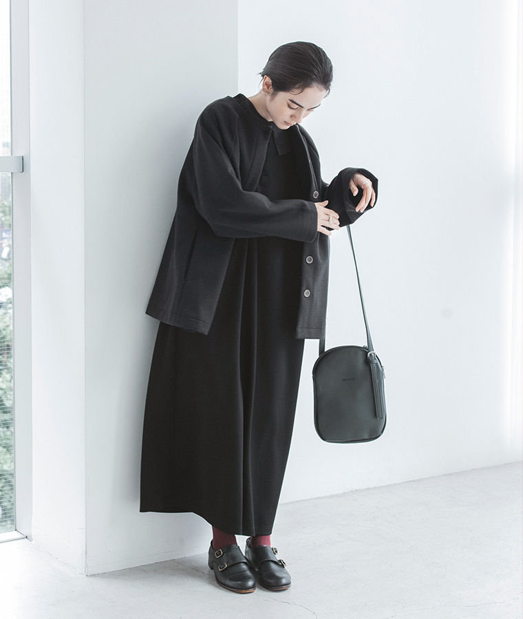 &yarn ブラックのプリーツ襟ワンピースにカーディガンとショルダーバッグを合わせた着こなし