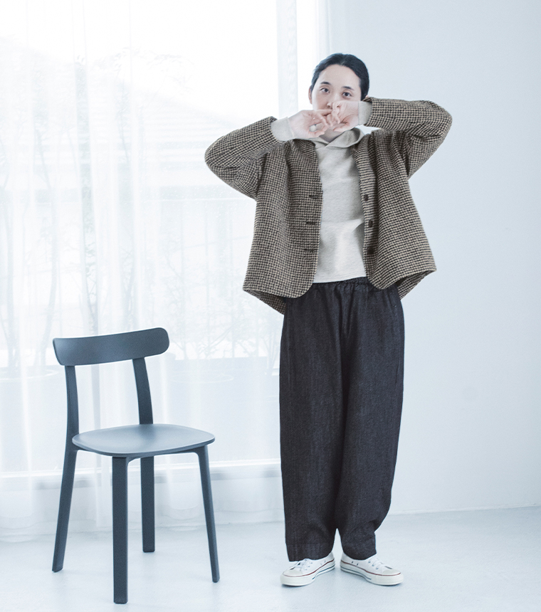 ベージュのチェック柄ジャケットを着て両腕を上げた女性モデル