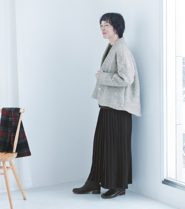 グレーのジャケットとプリーツスカートの横向きの全身スタイル