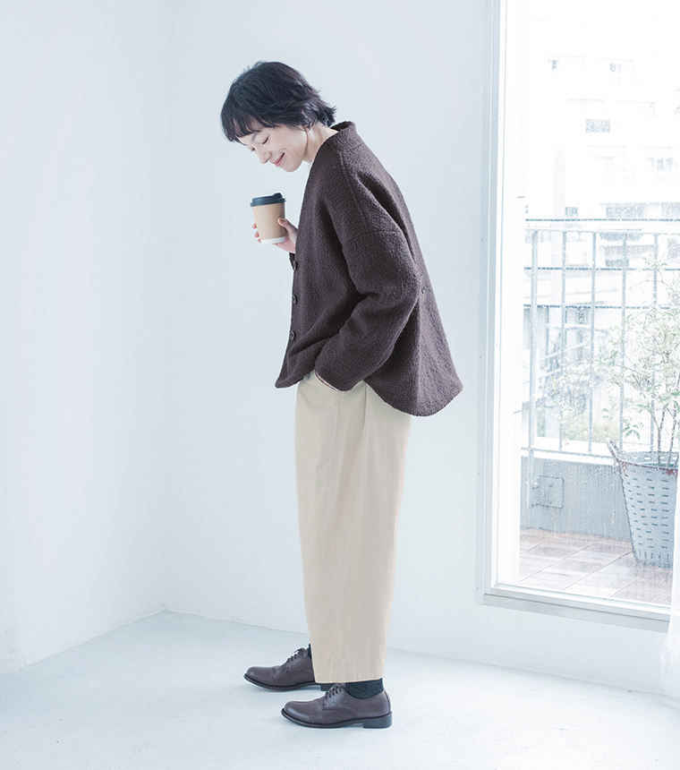 チャコールのジャケットとオフホワイトのパンツの横向きの全身スタイル