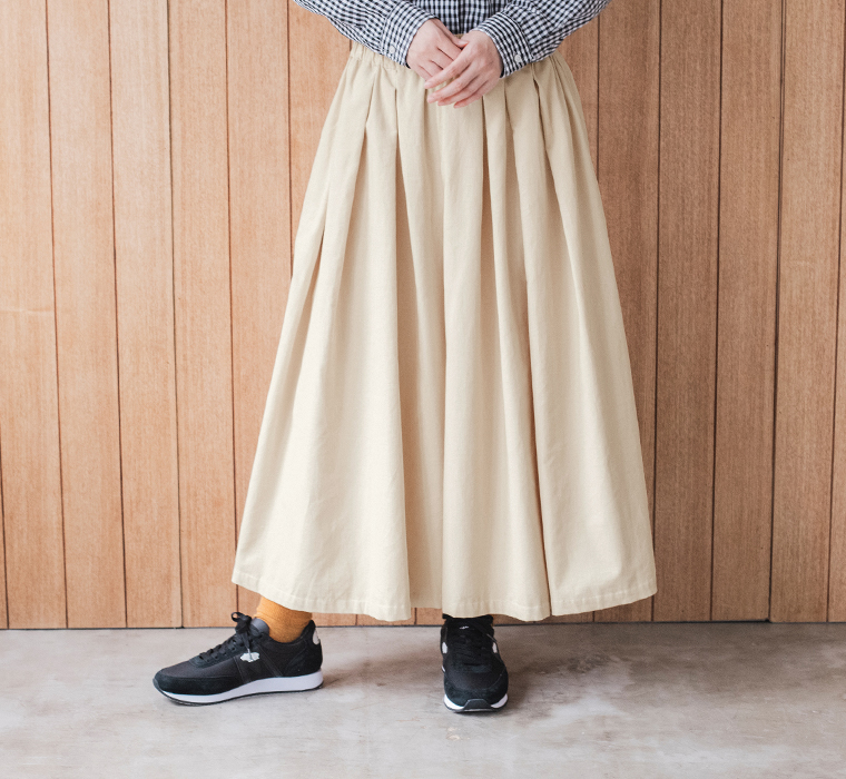 エクリュのコーデュロイタックワイドパンツ。たっぷりとした生地使いと美しいタックが特徴