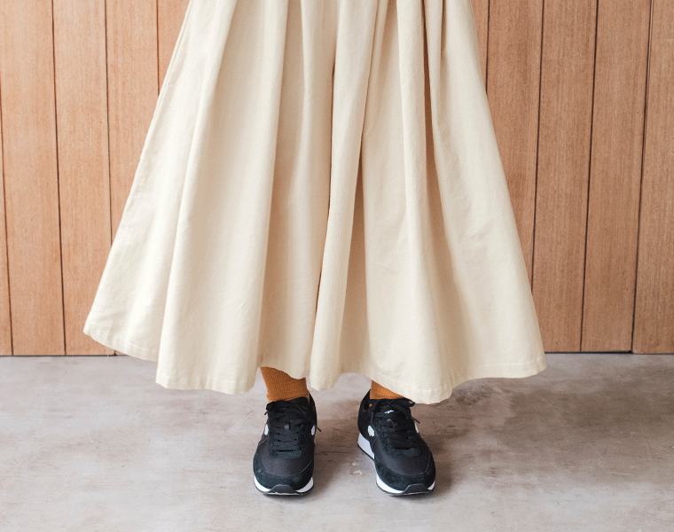 &yarnのエクリュのコーデュロイタックワイドパンツ。ふんわり広がる裾のシルエットと黒スニーカーを合わせた足元コーデ