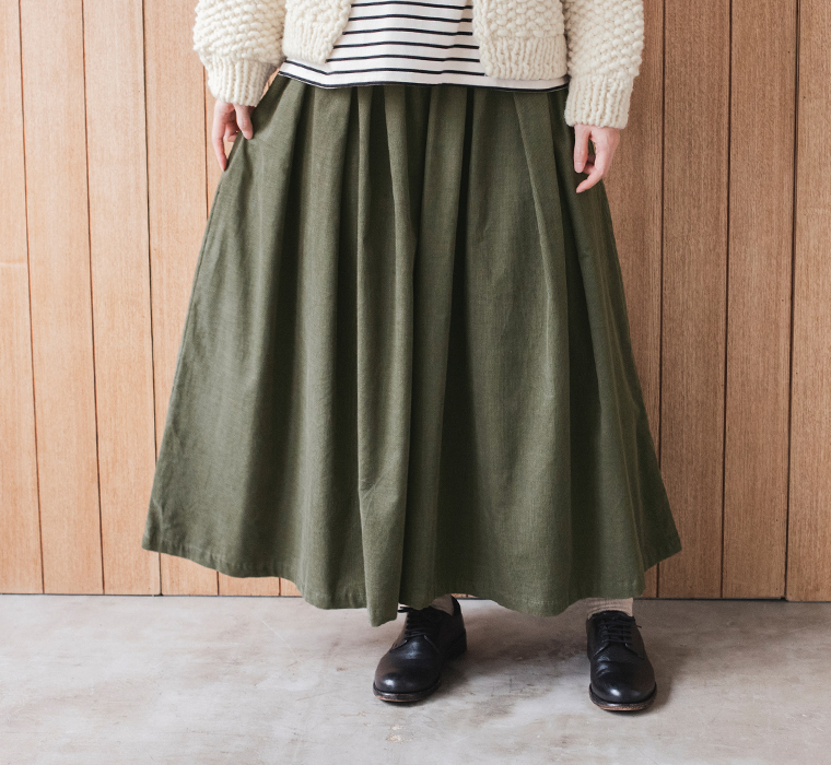 カーキのコーデュロイタックワイドパンツ。ウエストから広がるタックとスカートのようなボリュームシルエット