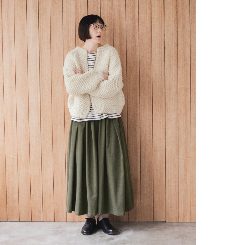 カーキのコーデュロイタックワイドパンツに白のニットカーディガンとボーダーカットソーを合わせた冬のレイヤードコーデ