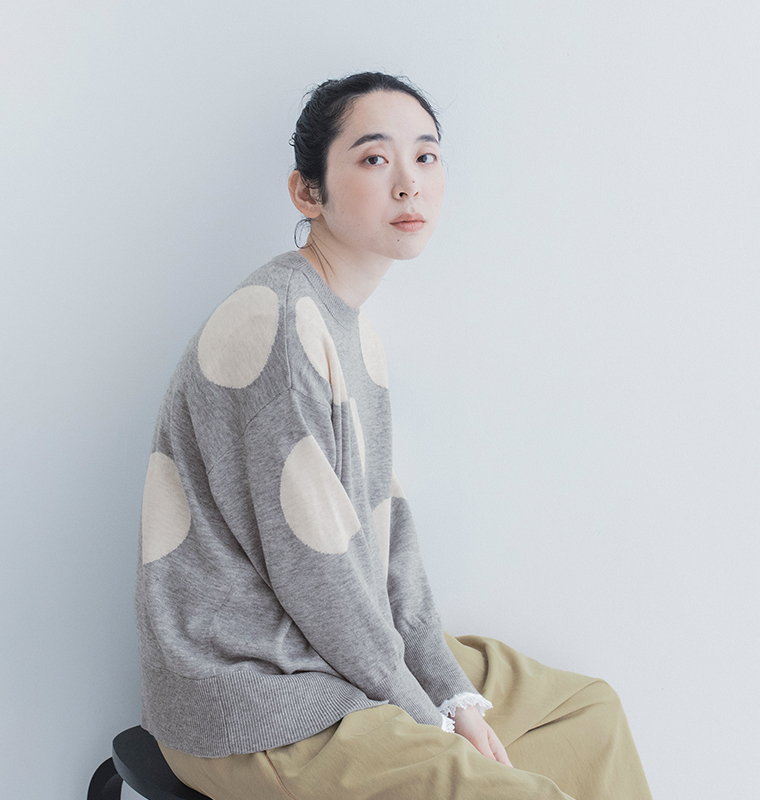 グレーのドットインターシャゆるプルニットを着用した、ゆったりとした身幅やドロップショルダーがわかる横向きの着用イメージ