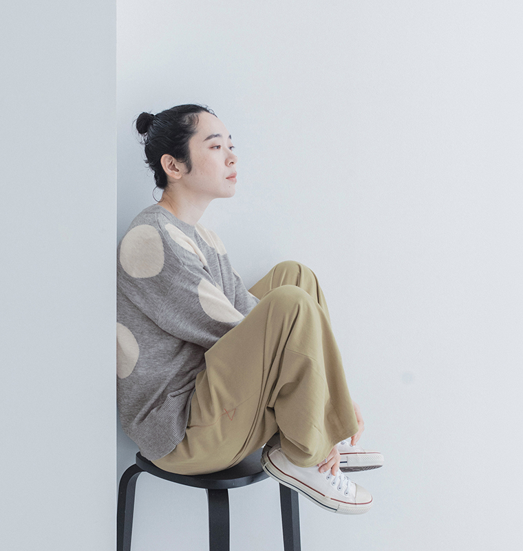 グレーのドットインターシャゆるプルニットにベージュのワイドパンツと白いスニーカーを合わせた、リラックス感のあるカジュアルスタイル