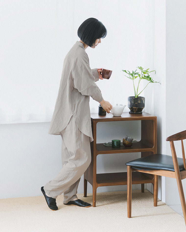 着る保湿クリーム(R)×TERAX 温活・血行促進パジャマ（グレー）を着用し、テーブルでお茶の準備をする着用イメージ