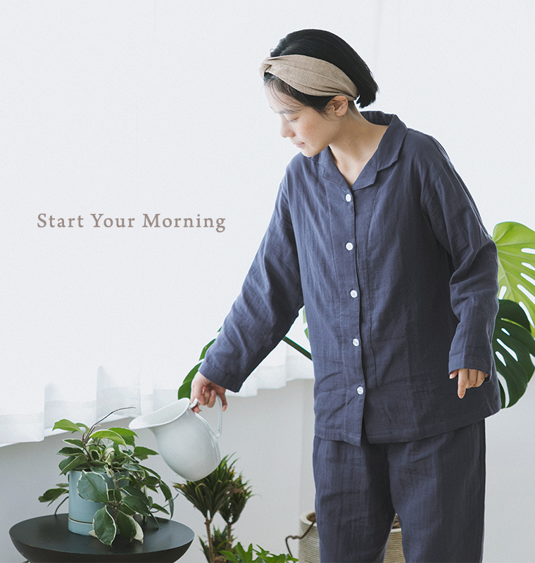 着る保湿クリーム(R) 前開きテーラーカラーパジャマ（ネイビー）を着用し、観葉植物に水やりをする着用イメージ