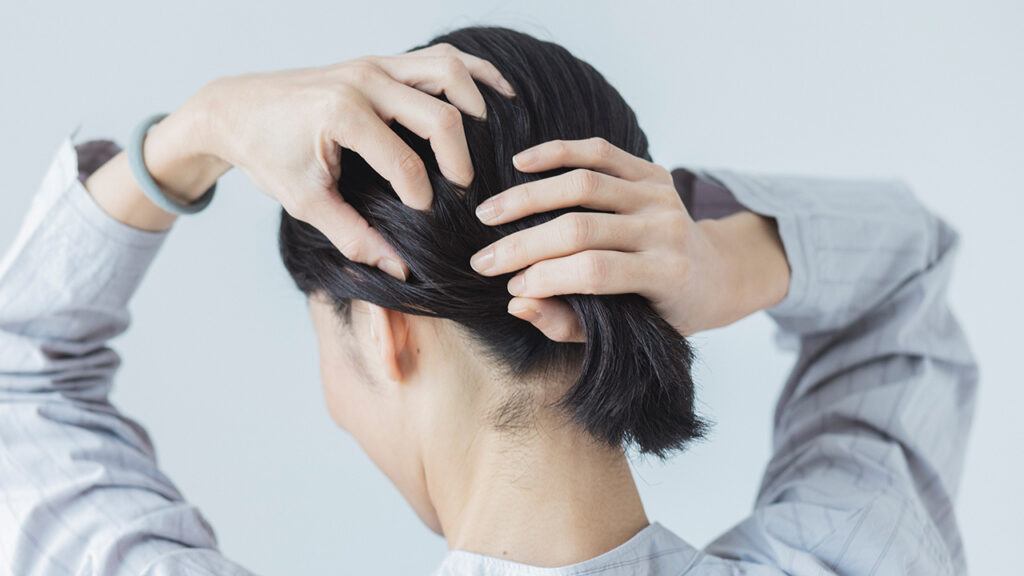 手ぐしでひとつに髪をまとめる女性