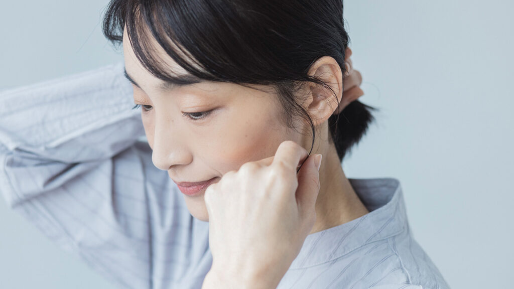 もみあげの髪を指で引き出す女性