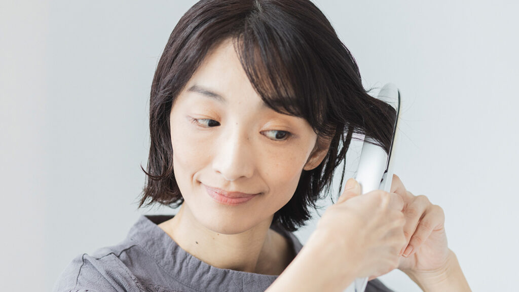 ストレートアイロンでサイドの髪を乾かす女性